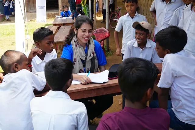 A volunteer talks with students gathered around the registration table