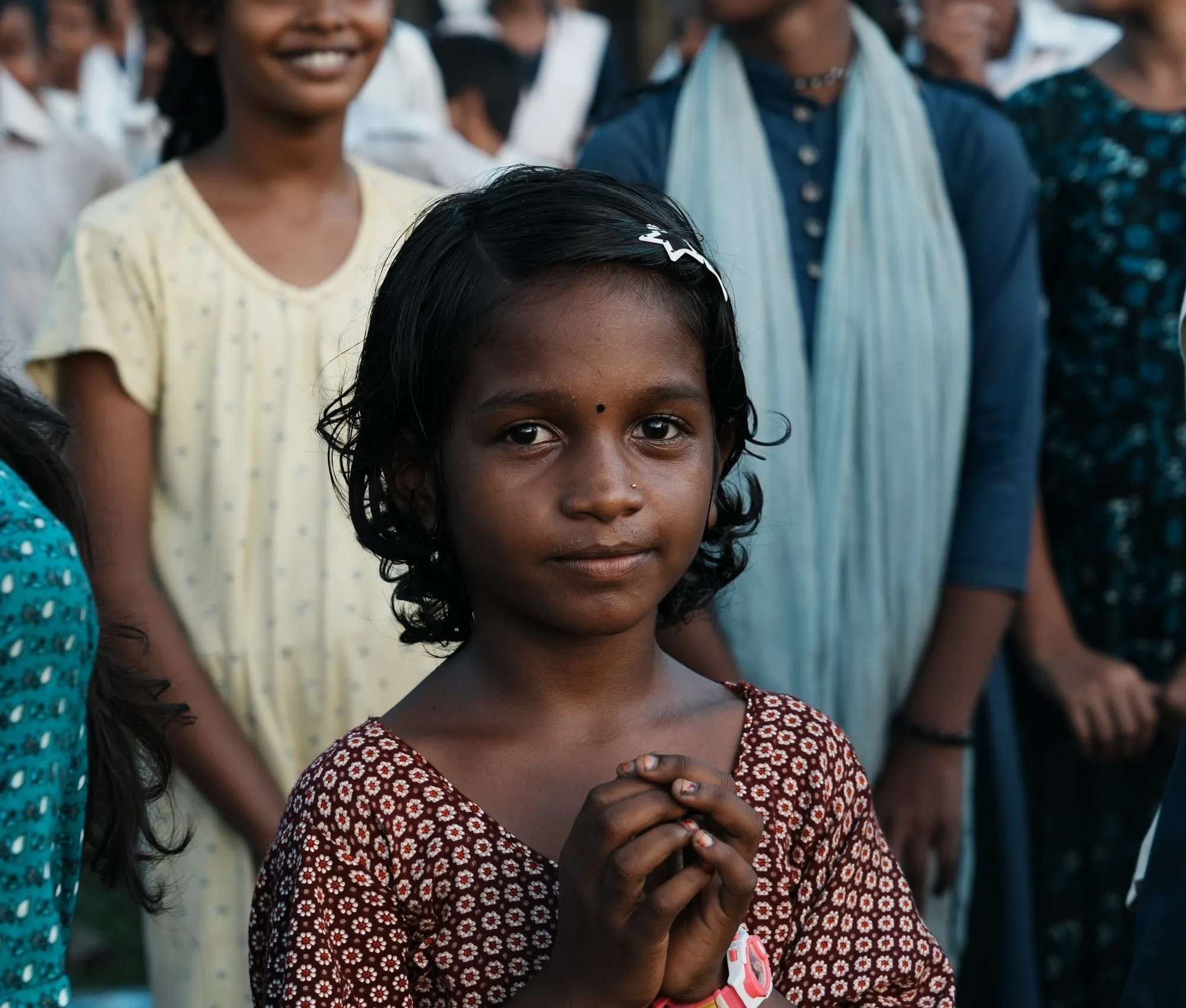 A young girl of the tea garden community, hands clasped, at a Dreams & Ink gathering