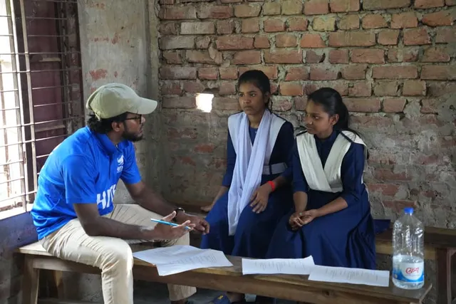 A HITH volunteer listens to two students inside their classroom