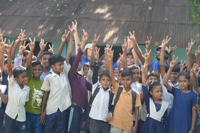 Dozens of schoolchildren cheering in front of their schoolhouse