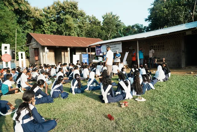 Students seated on the field facing the school during the event