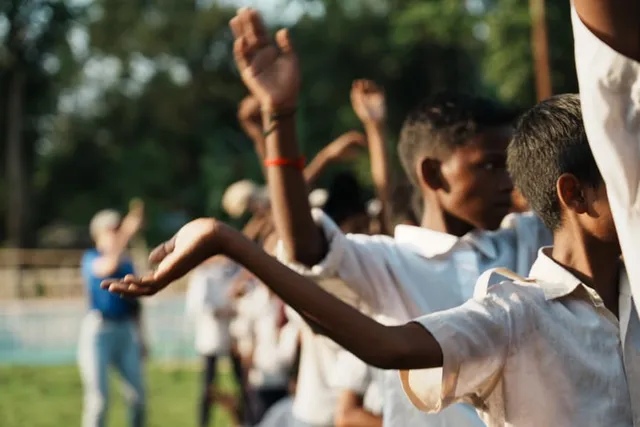 Boys stretching their arms in a group game in golden light
