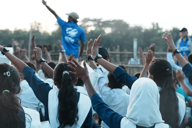 Children raise their hands together during the assembly