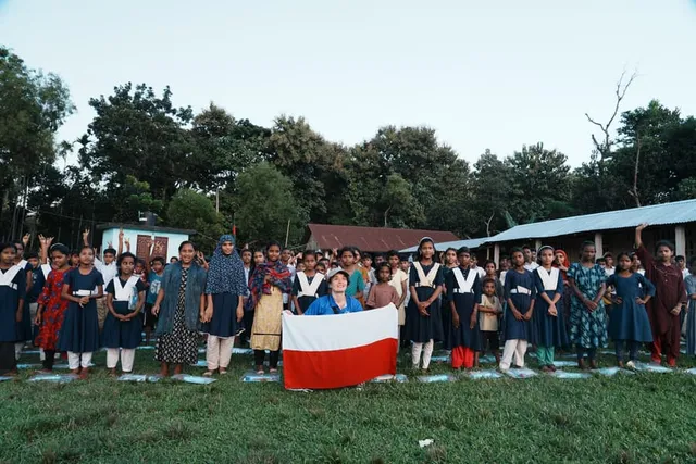 A volunteer kneels for a group photo with the children