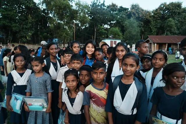 Children cluster around a smiling volunteer for a photo
