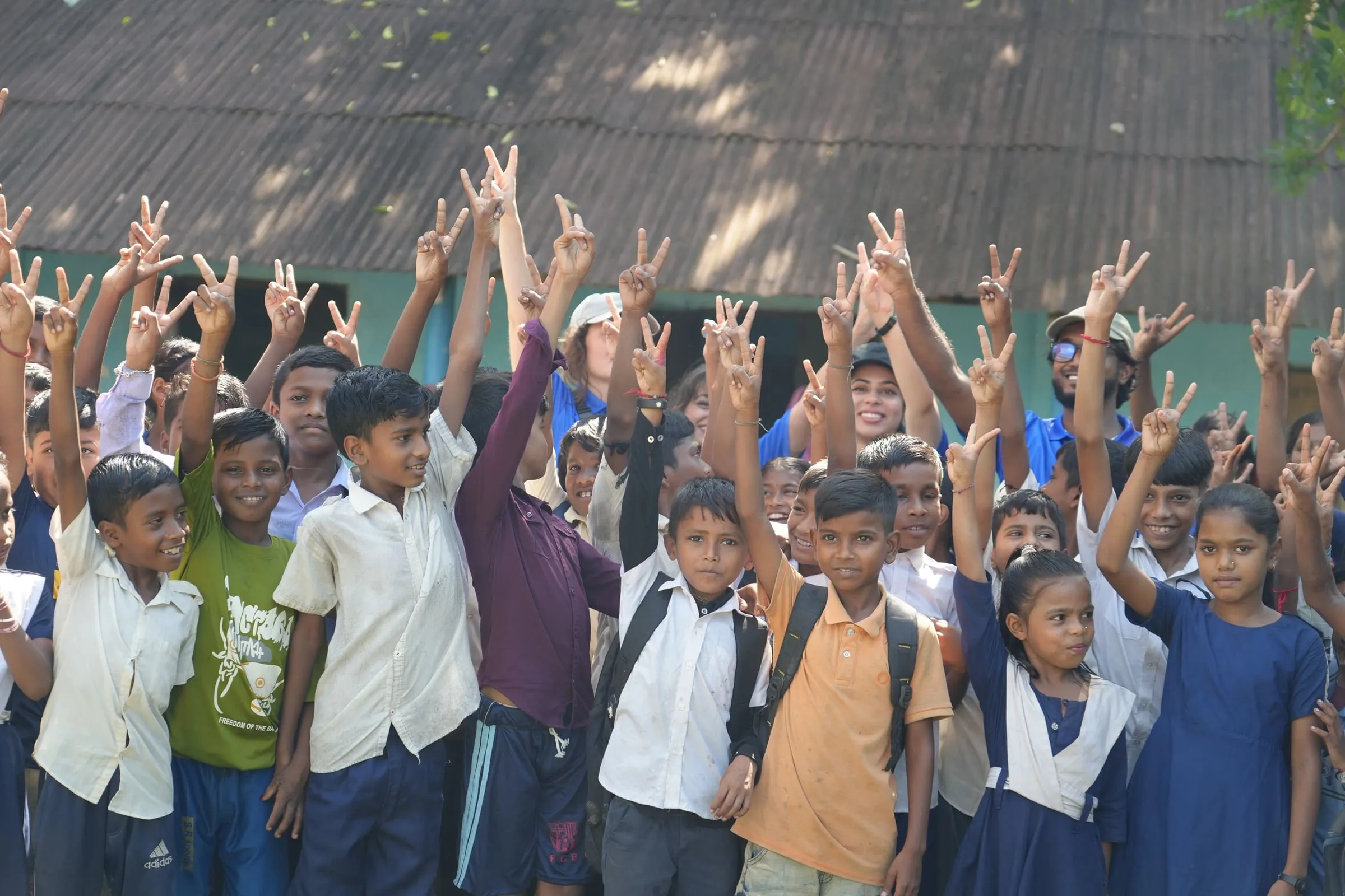 Schoolchildren cheering in front of their schoolhouse